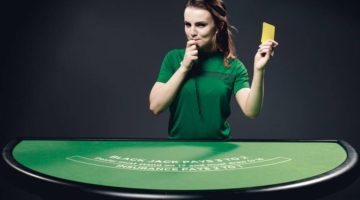 Live casino dealer holds yellow card.