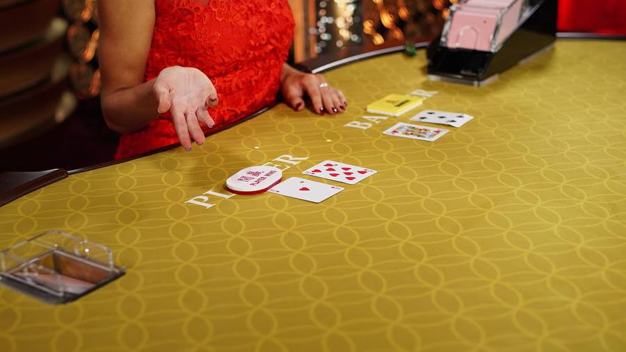 Dealer pointing at baccarat cards